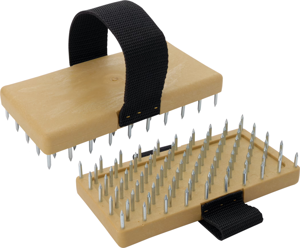 A detailed view of a foot massage device featuring two flat wooden bases with metallic spikes. The device has a sturdy black fabric strap for securing to the foot, enhancing stability during use. The upper piece can be seen slightly elevated above the lower piece, which is fully covered with metallic spikes for therapeutic foot pressure. The design promotes relaxation and pain relief through acupressure.