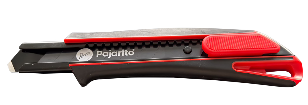 Pajarito_Dummy_Pajacut-2_176521_2023-11 Studio-style horizontal photo of a black and red retractable utility knife (snap-off segmented blade) with the brand name 'Pajarito' printed on the side. The plastic handle is ergonomically shaped and features a textured red thumb slider and a red blade lock; the segmented metal blade is partially extended showing one cutting segment. Slight surface scratches and signs of use are visible. The object is isolated on a clean white background, suitable for cutting cardboard, paper and packaging; modern, compact design.
