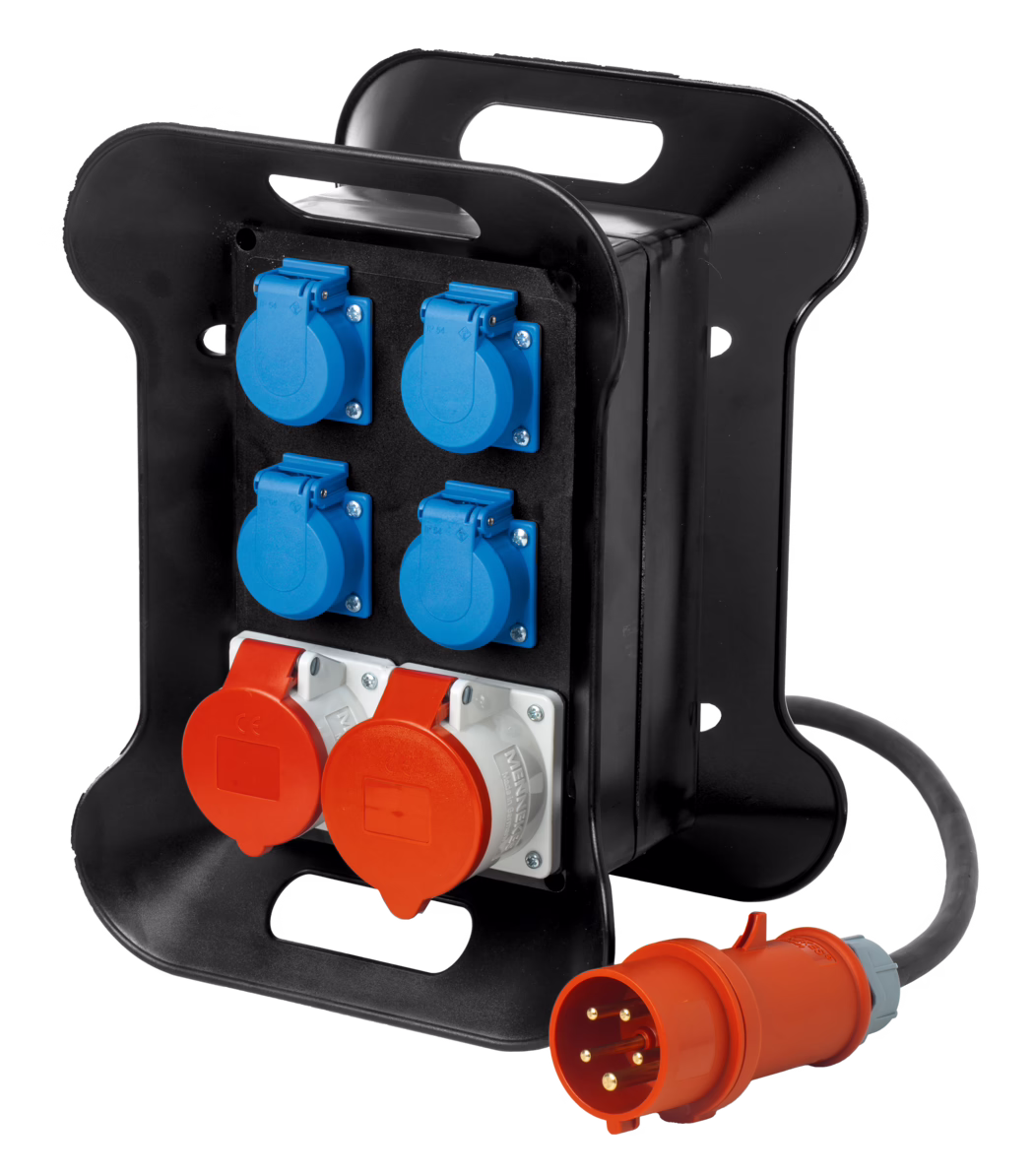 Pajarito_Dummy_Building site - power distributor_016917_2021-11 A portable power distribution unit with multiple sockets. The unit has a sturdy black casing with two red socket outlets at the bottom and four blue socket outlets on the front. It is designed for outdoor or industrial use, featuring durable materials and a rugged design for easy handling. A power cable with an orange connector extends from one side of the unit.