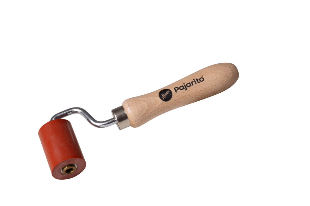 A small yet sturdy paint roller with a red roller head and a wooden handle. The handle is engraved with the brand name 'Pajarito'. It is designed for easy grip and application of paint on various surfaces.