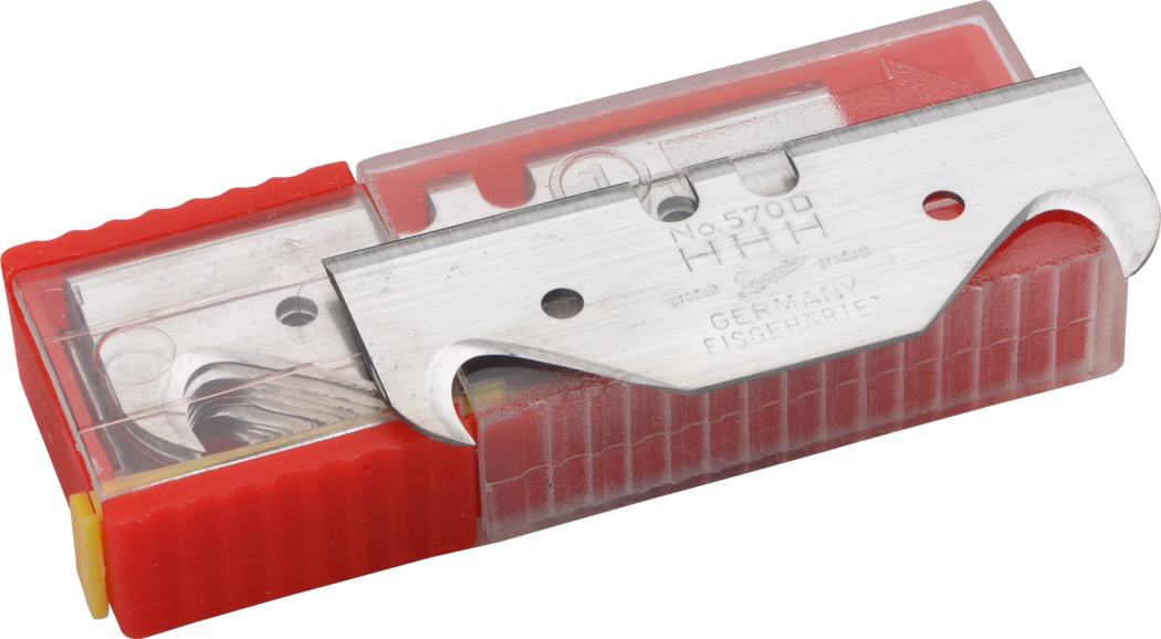 A close-up view of a razor blade in a protective red case, with the blade visible showing its sharp edge. The blade features engraving indicating it's made in Germany and its model number. The case is transparent on top, allowing a view of the blade inside, and has a ridged texture on the sides for grip.