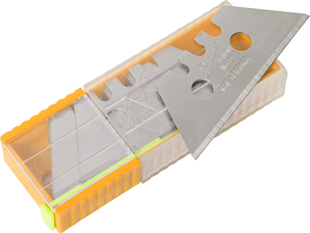 A close-up image of a metal utility blade housed in a transparent plastic case. The blade is silver and sharp with notches cut into the edge, reflecting light. The case has an orange side and includes yellow and green accent colors, and is designed to securely hold the blade while allowing visibility. The background is neutral, focusing attention on the blade and its casing.