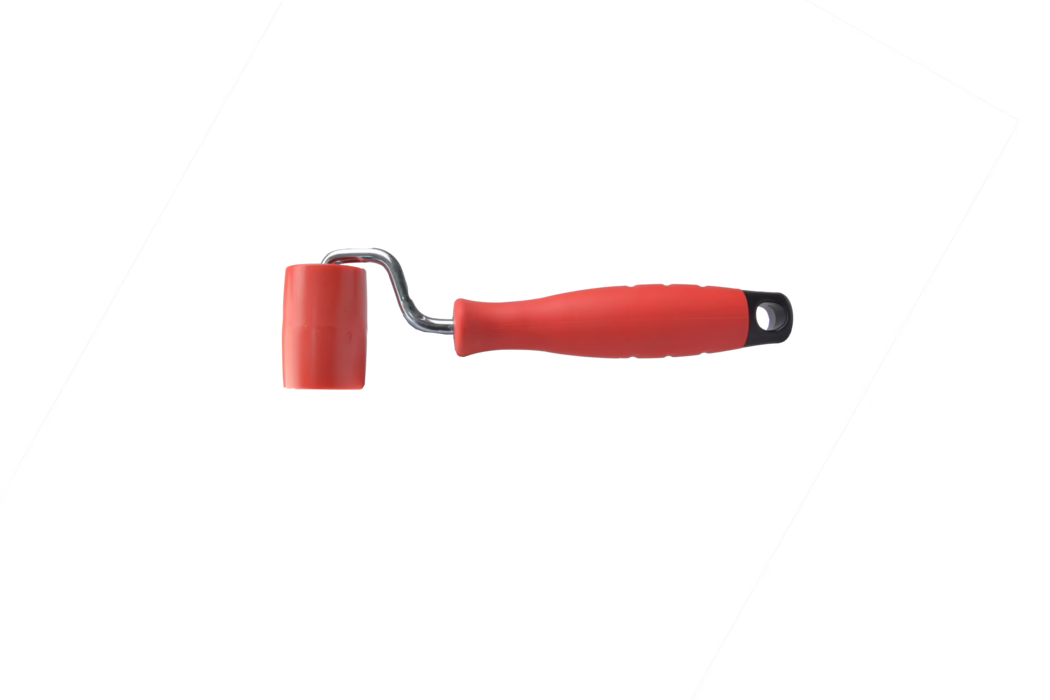 A small hand roller with a bright red rubber drum mounted on a short chrome metal frame and an ergonomic red plastic handle with a black end cap and a hanging hole. The roller head is made of smooth rubber suitable for applying pressure, smoothing wallpaper seams, or working with adhesives and craft surfaces; the compact construction makes it useful for detail work and narrow areas. The tool is photographed on a clean white background with the handle extending to the right and the roller head on the left.
