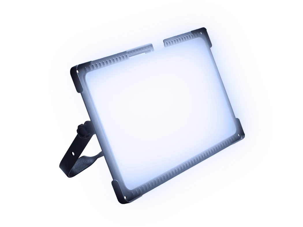 Close-up of a professional LED panel light tilted at an angle and emitting a bright cool white glow. The anodized aluminium frame and protective corner brackets are visible, with ventilation slots along the top edge and an adjustable black mounting bracket with a tightening knob. High-key composition on a white background with a subtle blue tint highlights the precise edges, textured metal surfaces and industrial design.